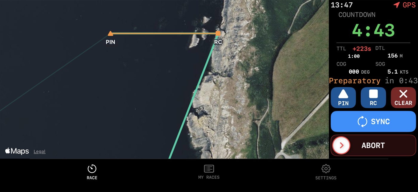 The app in landscape: a satellite map filling most of the screen with the start line drawn in orange between marks labelled PIN and RC, a green GPS track approaching from the south, the Cornish coastline on the right, and an instrument column showing countdown 4:43, Preparatory in 0:43, time to line 1:00, distance to line 156 metres, speed 5.1 knots, with PIN, RC, CLEAR, SYNC and a slide-to-confirm ABORT.